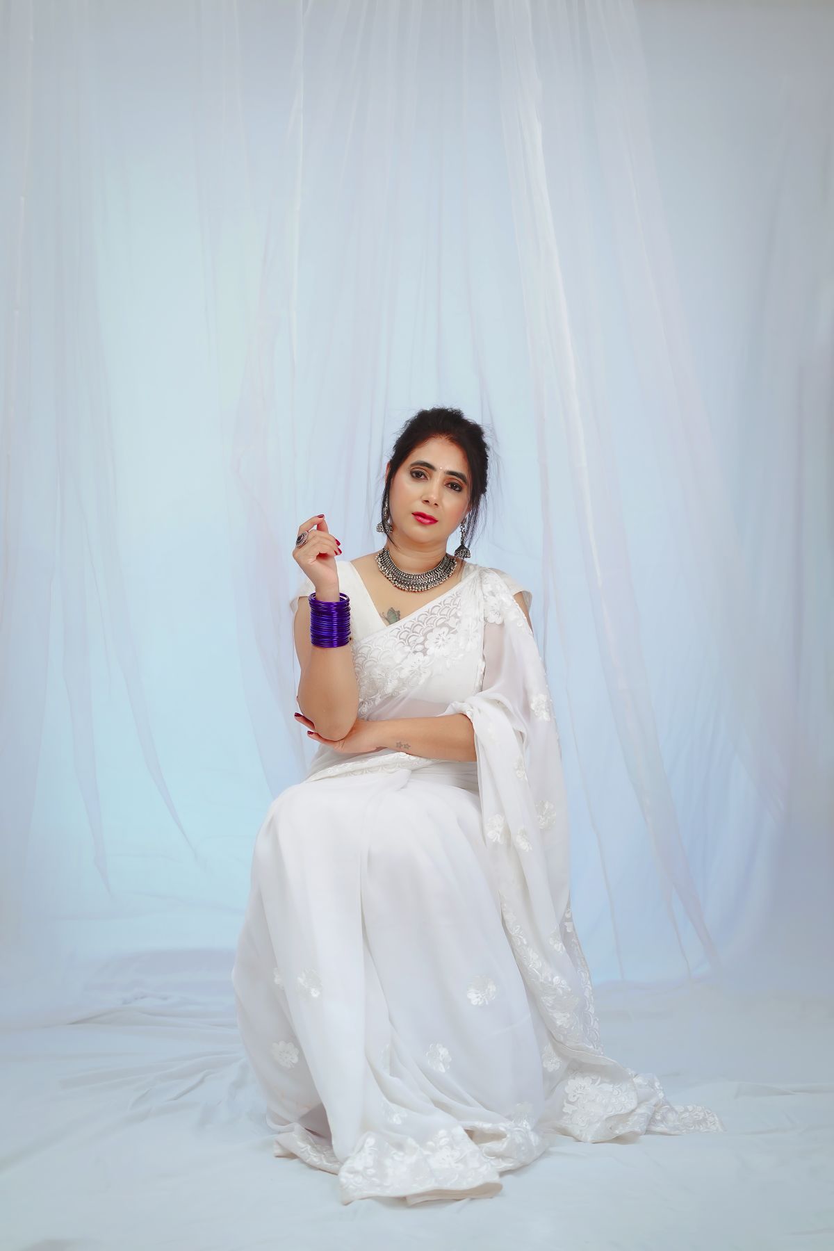 Editorial studio portrait of a client in a designer silk saree