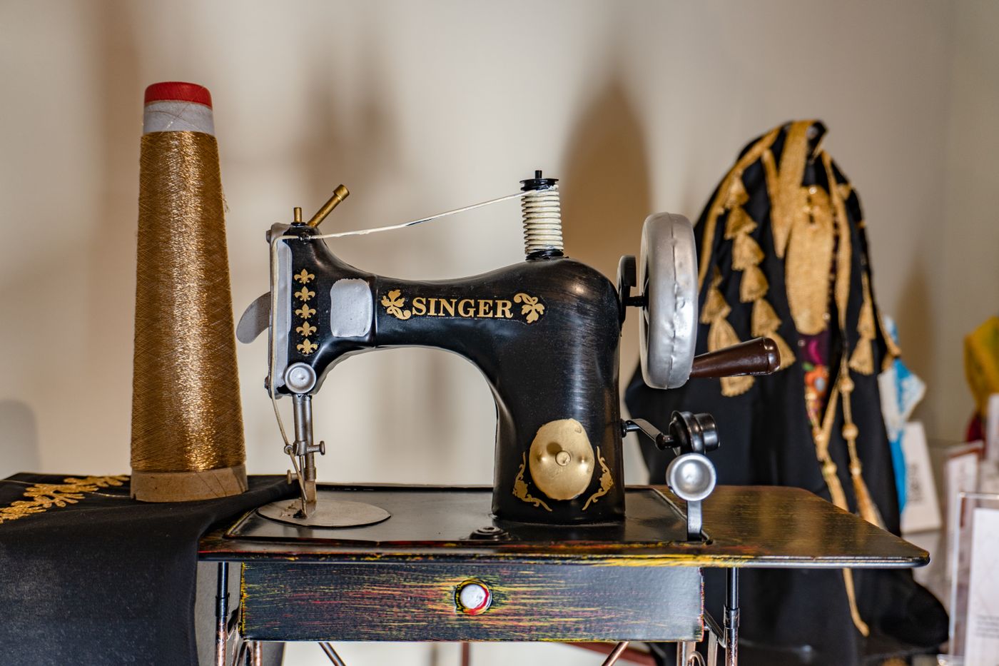 Vintage sewing machine with gold embroidery thread in the atelier